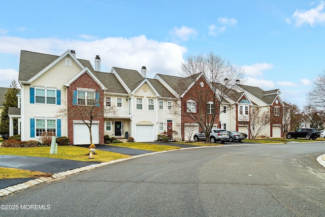 view of front of property featuring driveway, a residential view, a front yard, a garage, and a chimney