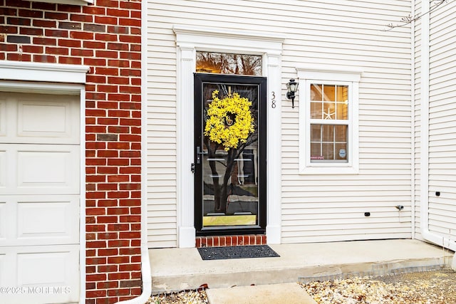 doorway to property with brick siding and a garage