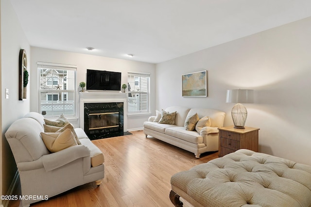 living room featuring a wealth of natural light, light wood-type flooring, and a high end fireplace