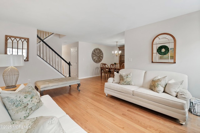 living area with stairway, wood finished floors, baseboards, and a chandelier