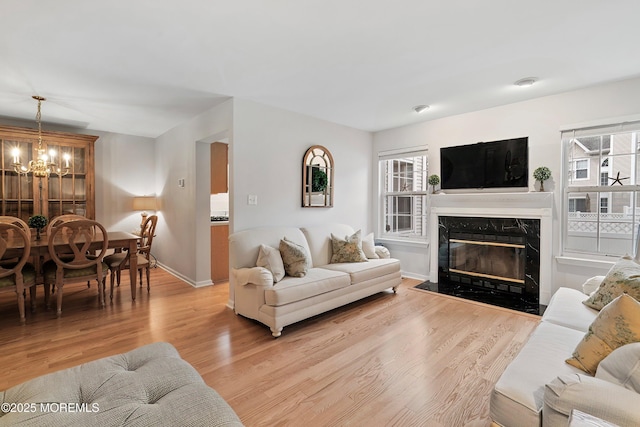 living area featuring a wealth of natural light, light wood-type flooring, and a chandelier