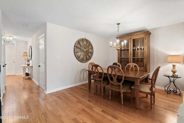 dining room featuring an inviting chandelier, light wood-style floors, and baseboards