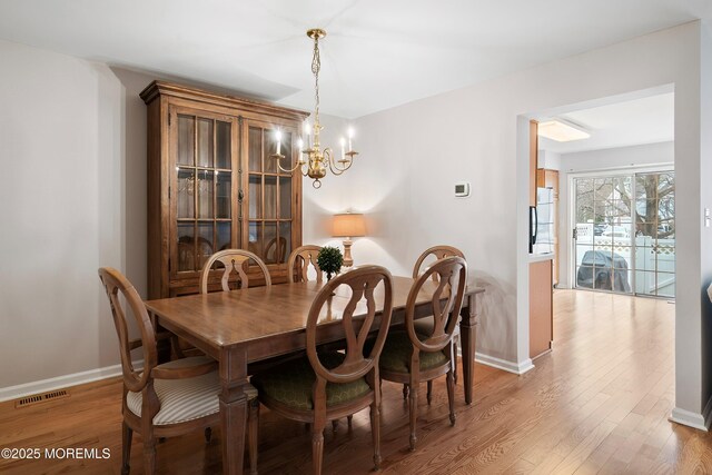 dining area with a chandelier, visible vents, light wood-type flooring, and baseboards