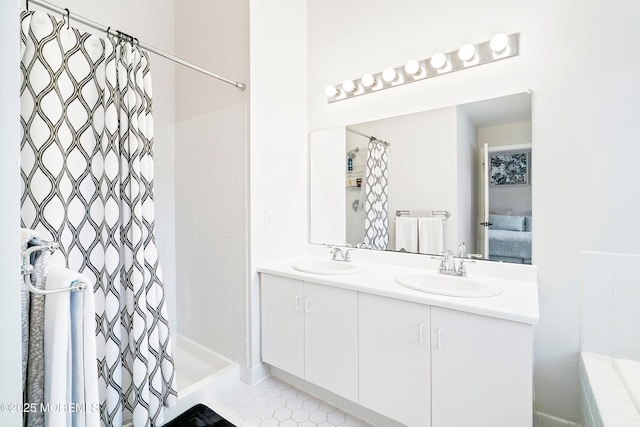 full bath featuring a tile shower, tile patterned flooring, double vanity, and a sink