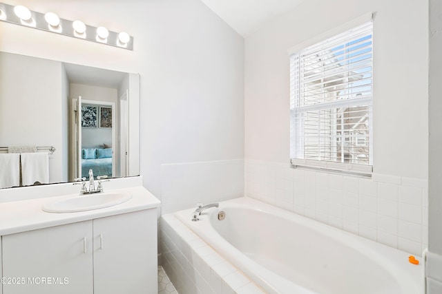 ensuite bathroom featuring connected bathroom, a bath, and vanity