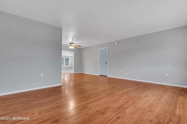 unfurnished room featuring a ceiling fan, baseboards, and light wood finished floors