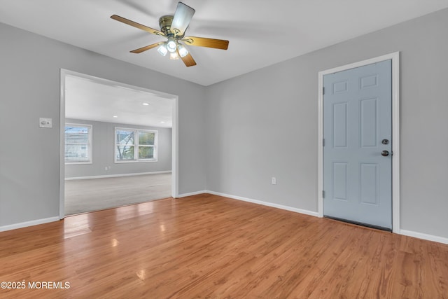 unfurnished room with baseboards, light wood-style floors, and a ceiling fan