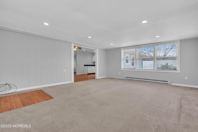 unfurnished living room featuring recessed lighting, baseboard heating, carpet flooring, and baseboards