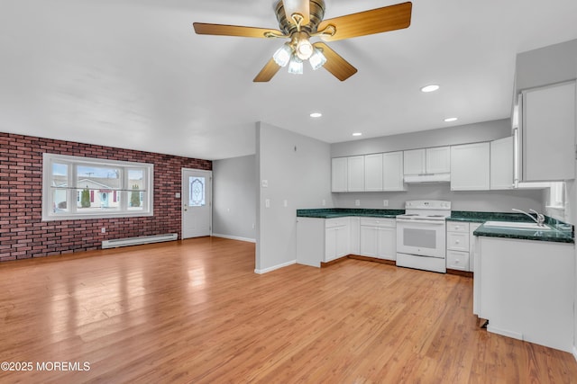 kitchen featuring white electric range, a baseboard heating unit, under cabinet range hood, dark countertops, and brick wall