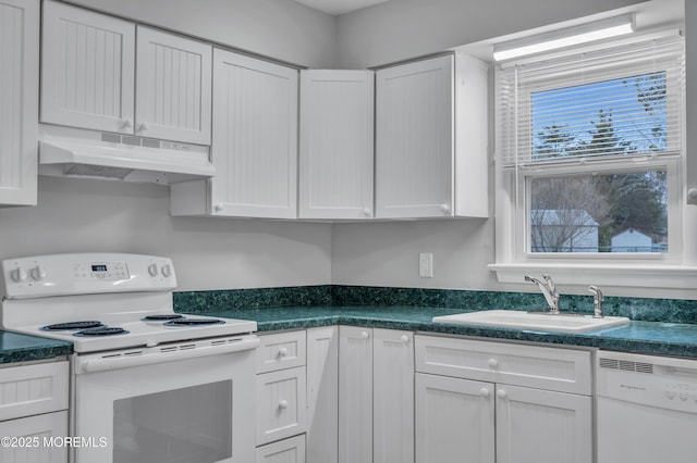 kitchen featuring under cabinet range hood, white appliances, dark countertops, and a sink