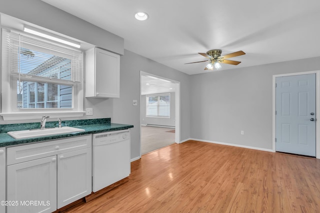 kitchen with dark countertops, white cabinets, dishwasher, and a sink