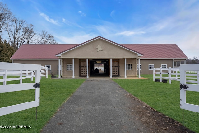 view of front of house with aphalt driveway, metal roof, a front lawn, and fence