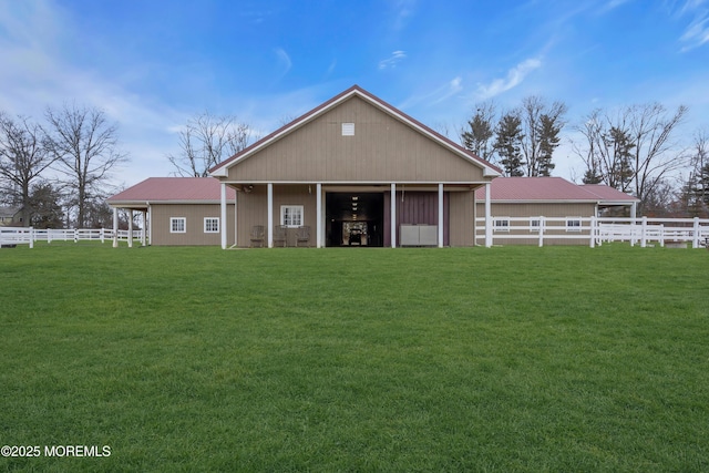 back of property with a lawn, an outdoor structure, and fence