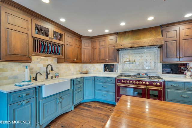 kitchen featuring premium range hood, a sink, range with two ovens, wooden counters, and dark wood-style flooring