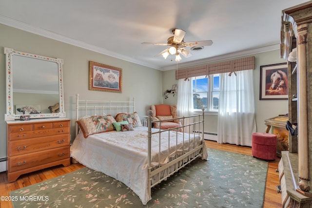 bedroom with ceiling fan, baseboard heating, wood finished floors, and crown molding