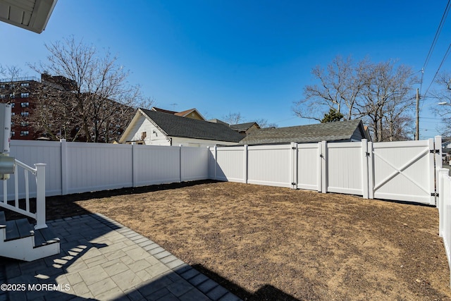 view of yard featuring a patio area, a fenced backyard, and a gate