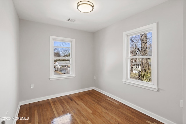 unfurnished room featuring visible vents, baseboards, and hardwood / wood-style flooring