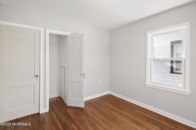 unfurnished bedroom with baseboards and dark wood-style flooring