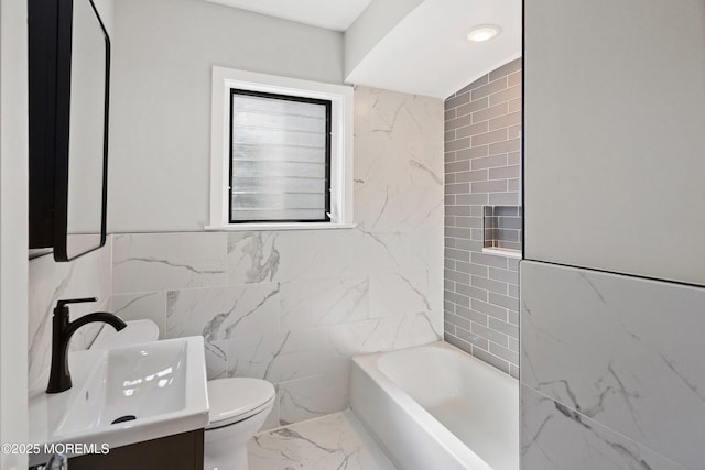 bathroom with tile walls, toilet, marble finish floor, and vanity