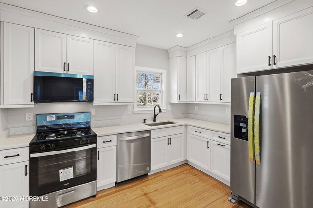 kitchen with visible vents, a sink, appliances with stainless steel finishes, white cabinets, and light countertops