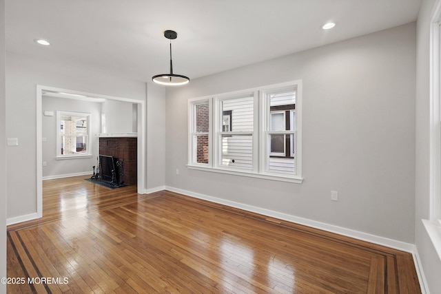 unfurnished living room featuring recessed lighting, baseboards, wood-type flooring, and a fireplace with flush hearth