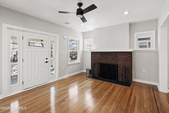 interior space featuring visible vents, a fireplace, hardwood / wood-style floors, and a ceiling fan