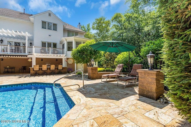 outdoor pool featuring outdoor dry bar, a patio area, and a pergola