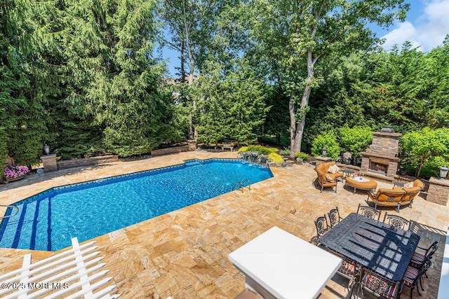 outdoor pool featuring outdoor dining area, a patio, and an outdoor stone fireplace