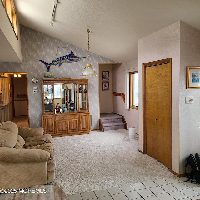 carpeted living area with stairway, lofted ceiling, rail lighting, a textured ceiling, and tile patterned floors