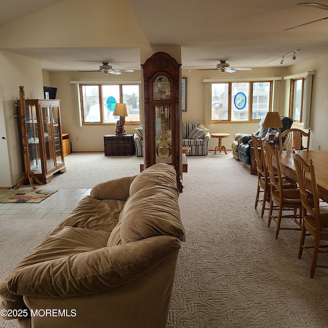 carpeted living room featuring tile patterned flooring, track lighting, lofted ceiling, and ceiling fan