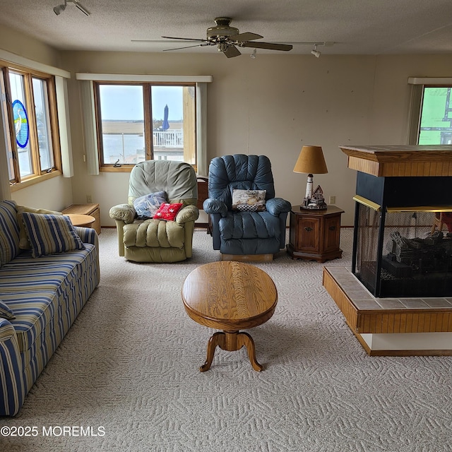 carpeted living room featuring track lighting, a textured ceiling, and ceiling fan