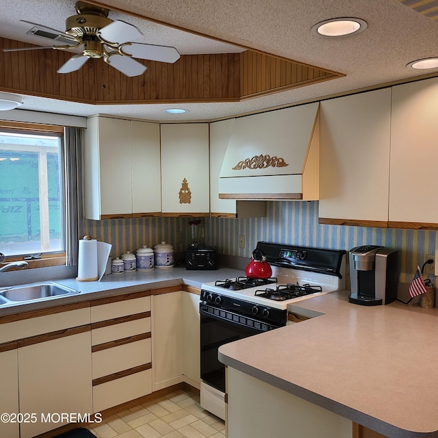 kitchen with a sink, light countertops, extractor fan, a textured ceiling, and gas range