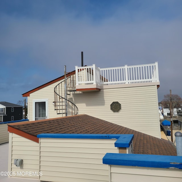 exterior space with stairway and roof with shingles