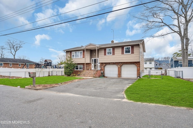 bi-level home featuring a front yard, an attached garage, fence, and driveway