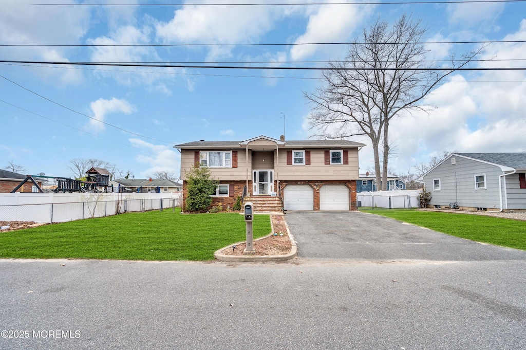 raised ranch featuring fence, a front lawn, a garage, aphalt driveway, and brick siding