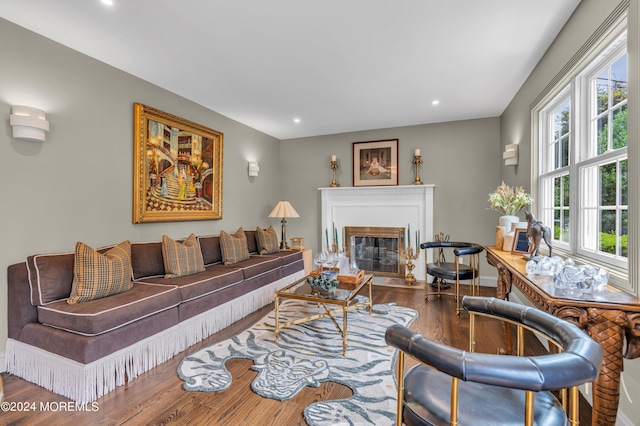 living room with a glass covered fireplace, recessed lighting, baseboards, and wood finished floors