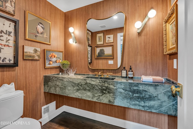 half bath featuring visible vents, toilet, wood finished floors, and vanity