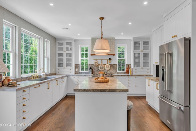 kitchen featuring visible vents, a kitchen island, a sink, appliances with stainless steel finishes, and backsplash