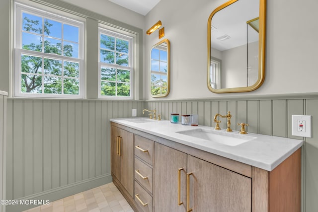 full bathroom featuring a sink, visible vents, double vanity, and wainscoting