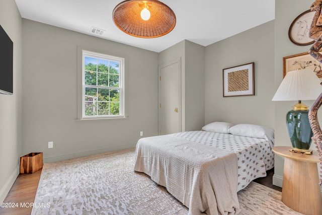 bedroom featuring wood finished floors, visible vents, and baseboards