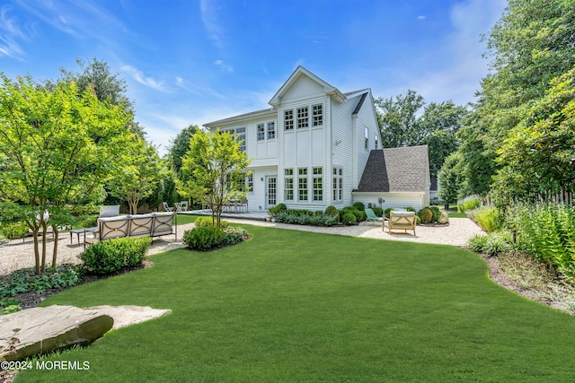 rear view of property featuring outdoor lounge area, a yard, a patio area, and board and batten siding