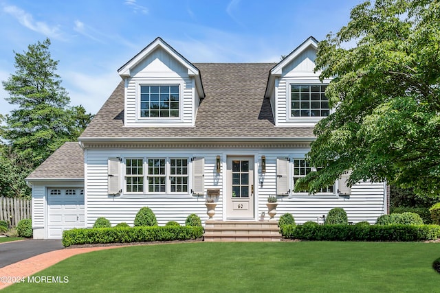 cape cod-style house featuring a front lawn, a garage, driveway, and a shingled roof