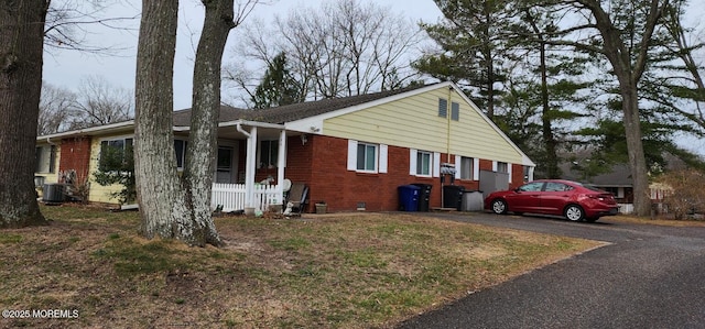 view of front of home featuring aphalt driveway, a porch, crawl space, brick siding, and central AC unit