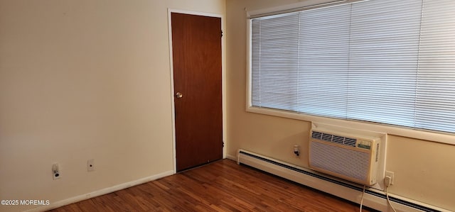 unfurnished room with a baseboard radiator, baseboards, and wood finished floors
