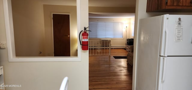 kitchen with a baseboard heating unit, freestanding refrigerator, and wood finished floors