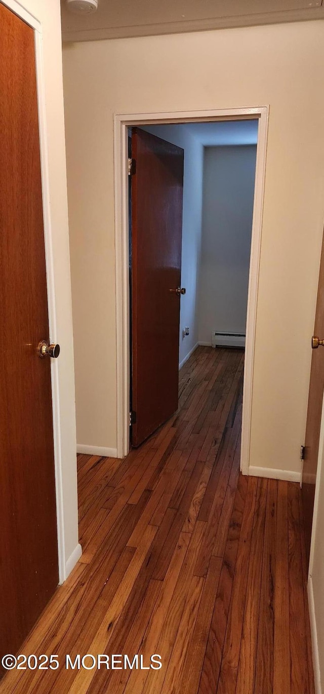 hall featuring hardwood / wood-style flooring, baseboards, and a baseboard radiator