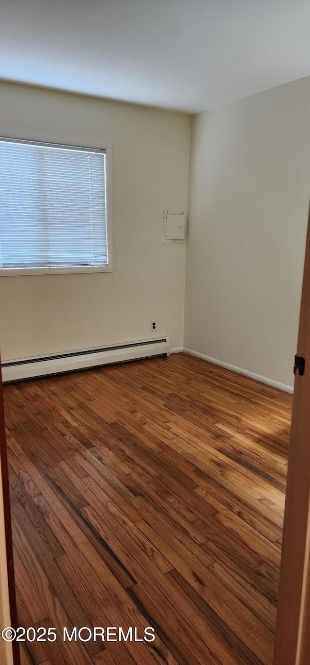 empty room with a baseboard heating unit and wood finished floors