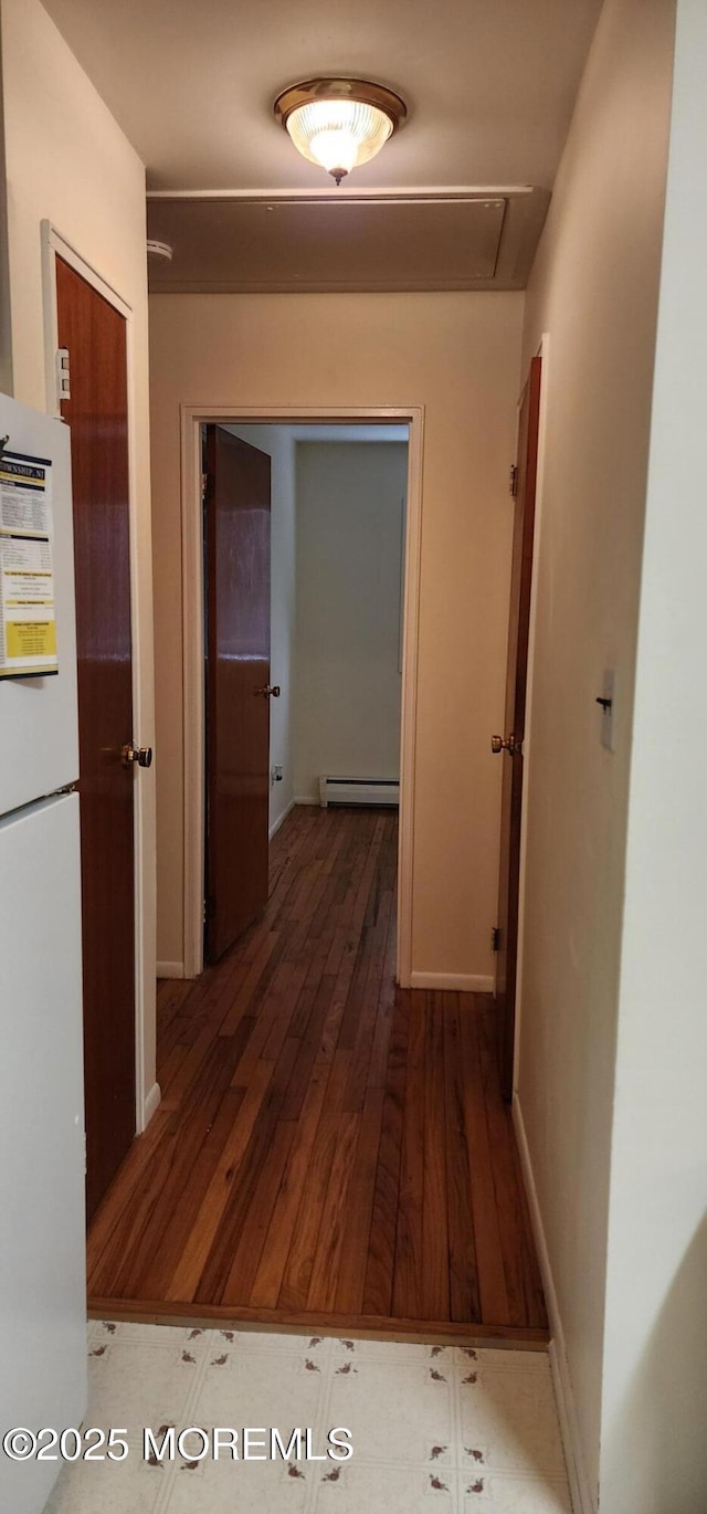 hallway featuring wood finished floors, baseboards, and a baseboard radiator