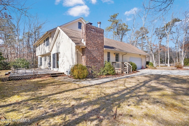 view of property exterior with a yard, a deck, a chimney, and a garage