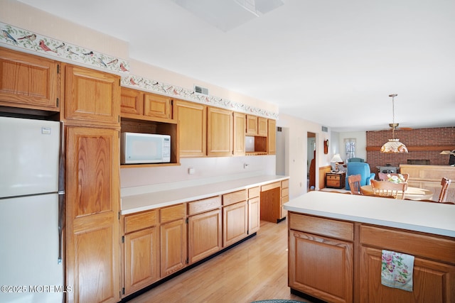 kitchen featuring visible vents, white appliances, light wood-type flooring, and light countertops